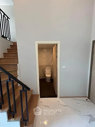 Modern home interior with staircase and bathroom entrance, featuring elegant marble flooring.