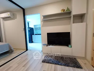 Modern living room with sleek TV unit and view into kitchen area
