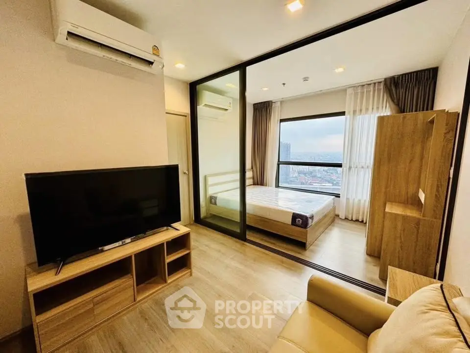 Modern apartment with spacious living room and bedroom, featuring large windows and wooden flooring.