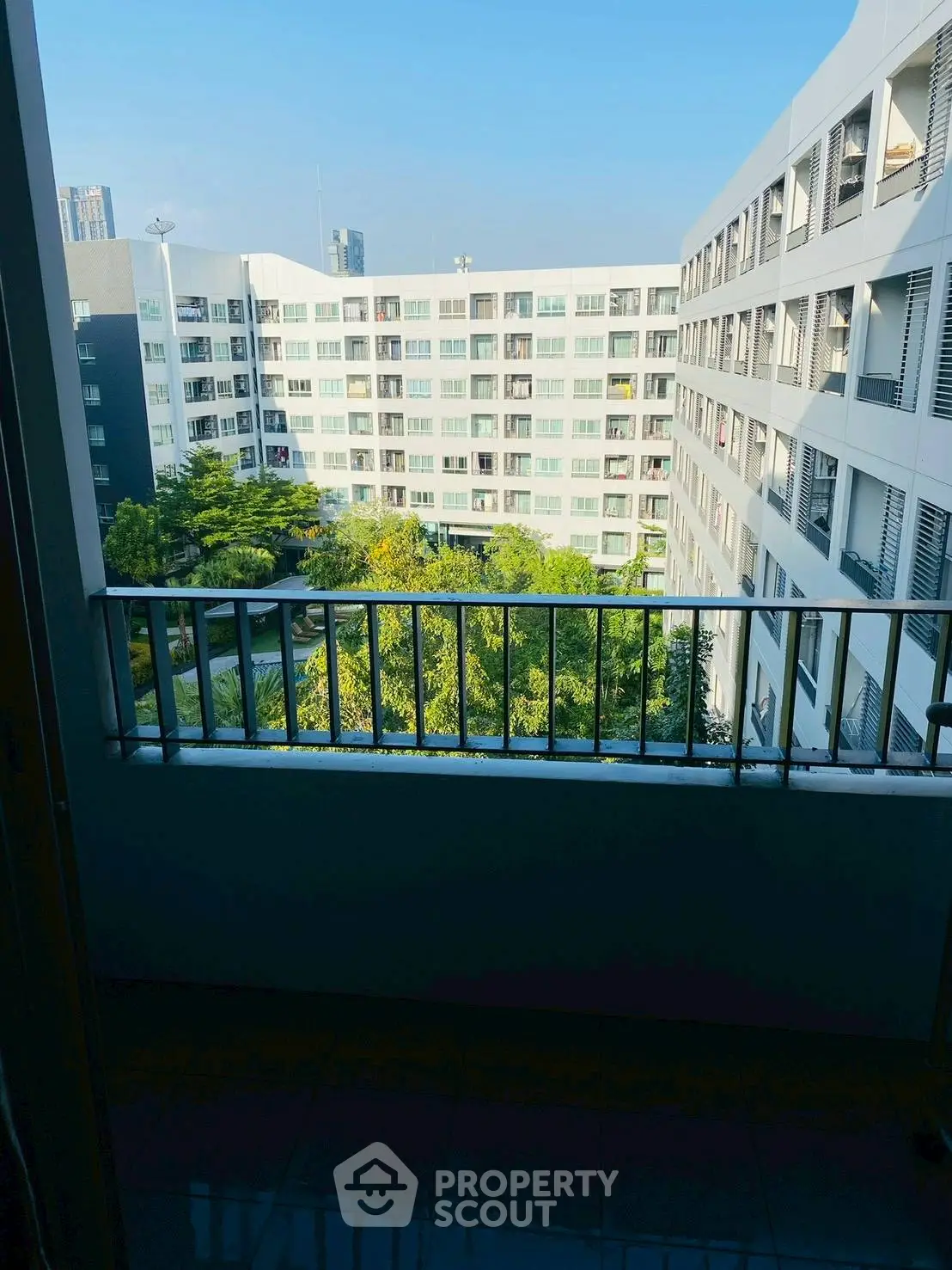 Spacious balcony with scenic view of modern apartment complex and lush greenery.