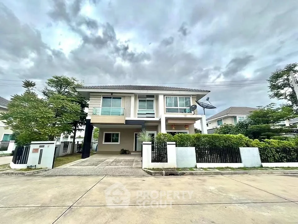 Modern two-story house with lush garden and driveway in suburban neighborhood.