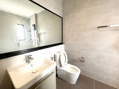 Modern bathroom with sleek fixtures and large mirror, featuring a stylish sink and toilet.