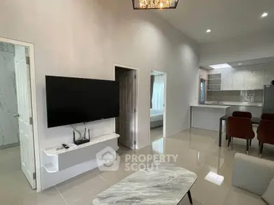 Modern living room with wall-mounted TV and open kitchen layout
