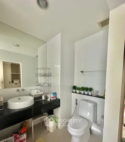 Modern bathroom with sleek fixtures and minimalist design, featuring a large mirror and stylish sink.
