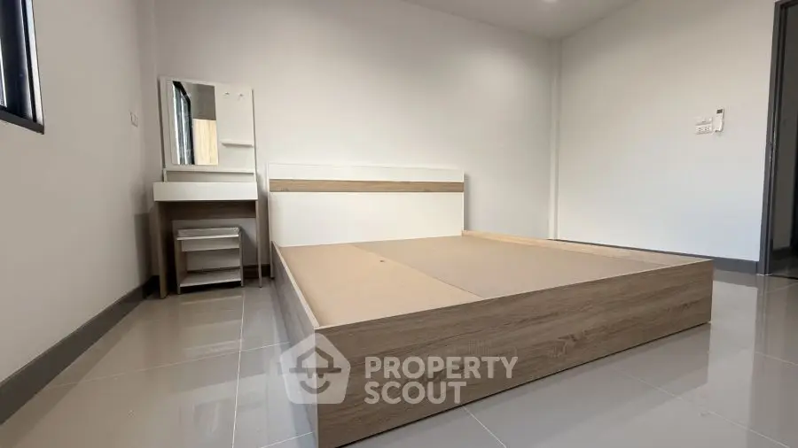 Minimalist bedroom with wooden bed frame and vanity set on glossy tiled floor.