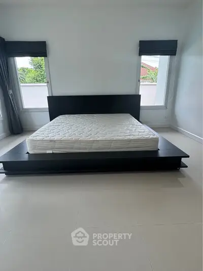 Spacious bedroom with modern bed frame and large windows