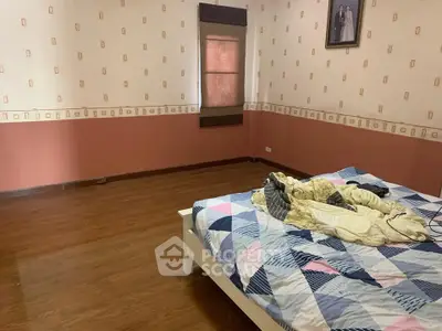 Spacious bedroom with wooden flooring and patterned wallpaper, featuring a cozy bed.