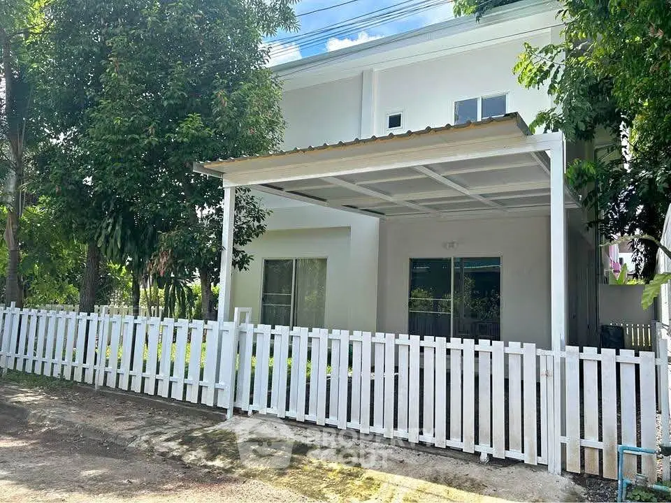 Charming white-fenced house with covered parking and lush greenery
