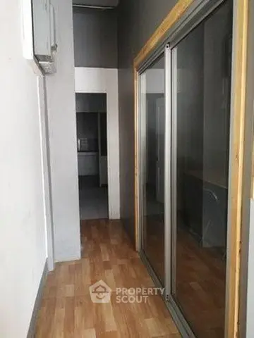 Spacious hallway with wooden flooring and sliding glass doors in modern apartment.