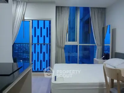 Modern bedroom with large windows and city view, featuring sleek design and natural light.