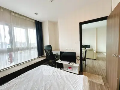 Modern bedroom with large windows and cozy workspace in a stylish apartment.