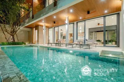 Luxurious modern home with stunning poolside view and elegant outdoor seating area.