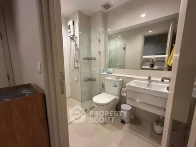 Modern bathroom with glass shower, sleek fixtures, and ample lighting.