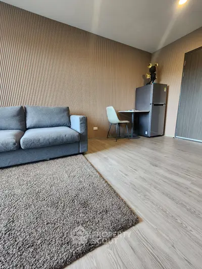 Modern living room with stylish sofa and dining area, featuring textured wall and sleek flooring.
