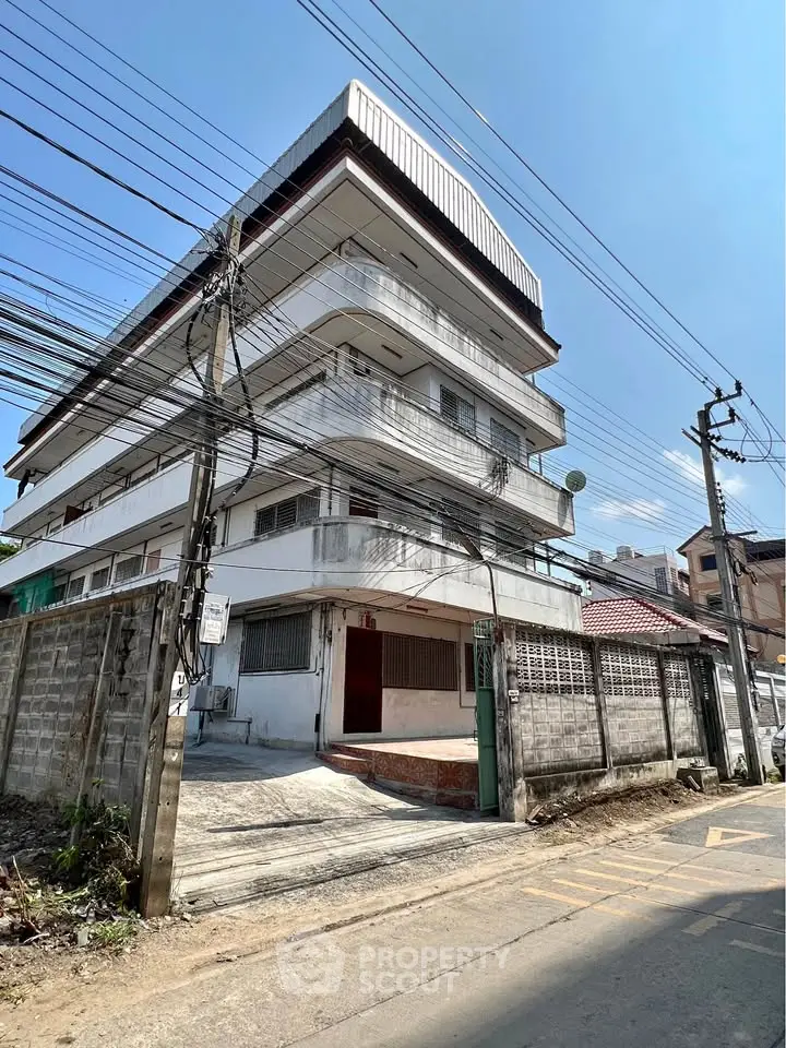 Four-story building with balconies on a sunny day, showcasing urban architecture.