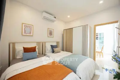 Modern bedroom with twin beds, stylish decor, and ample natural light