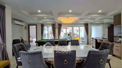 Luxurious open-plan living and dining area with pool table and elegant chandelier.