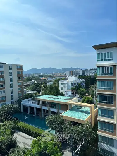Stunning view of modern apartment complex with pool and scenic mountain backdrop.