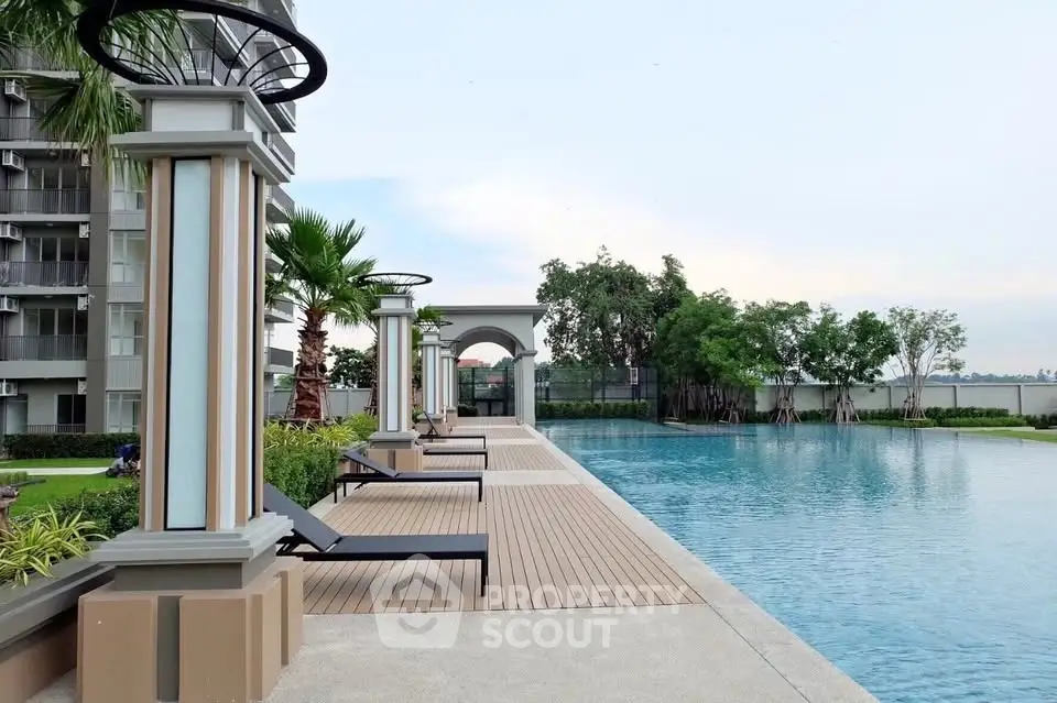 Luxurious poolside area with modern loungers and lush greenery in a high-end residential complex.