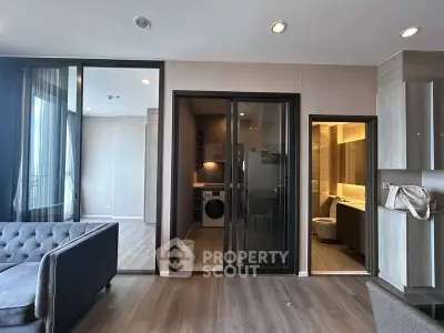 Modern apartment interior with living room, laundry area, and bathroom, featuring sleek design and ample natural light.