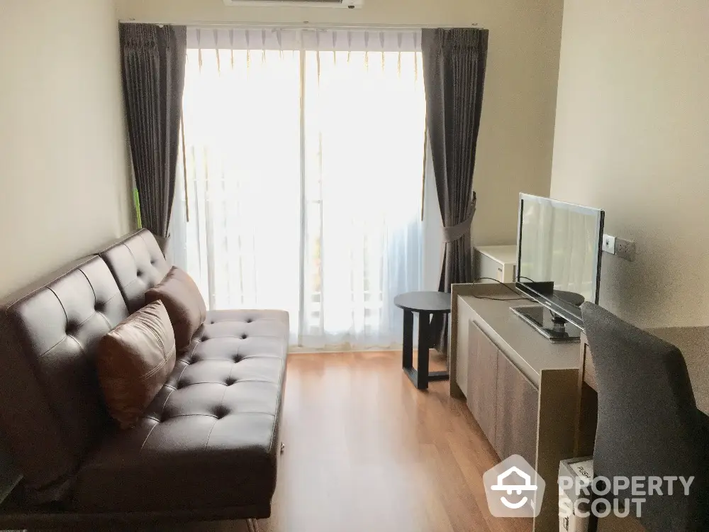 Cozy living room with modern sofa and TV, natural light through large window