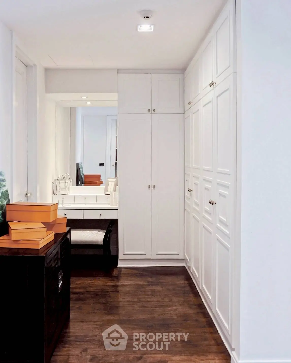 Elegant walk-in closet with white cabinetry and hardwood floors