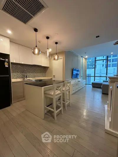 Modern open-layout kitchen and living room with stylish lighting and sleek design.