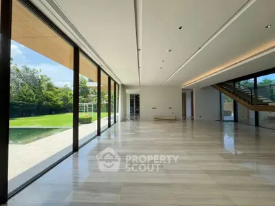 Spacious modern living room with floor-to-ceiling windows and garden view.