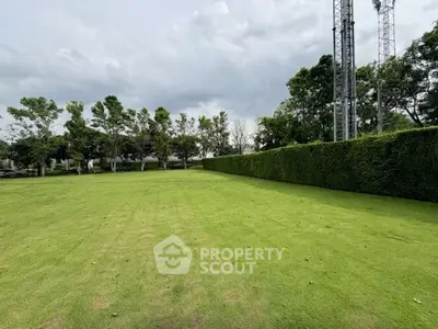Expansive green lawn with lush trees and hedges, perfect for outdoor activities and relaxation.