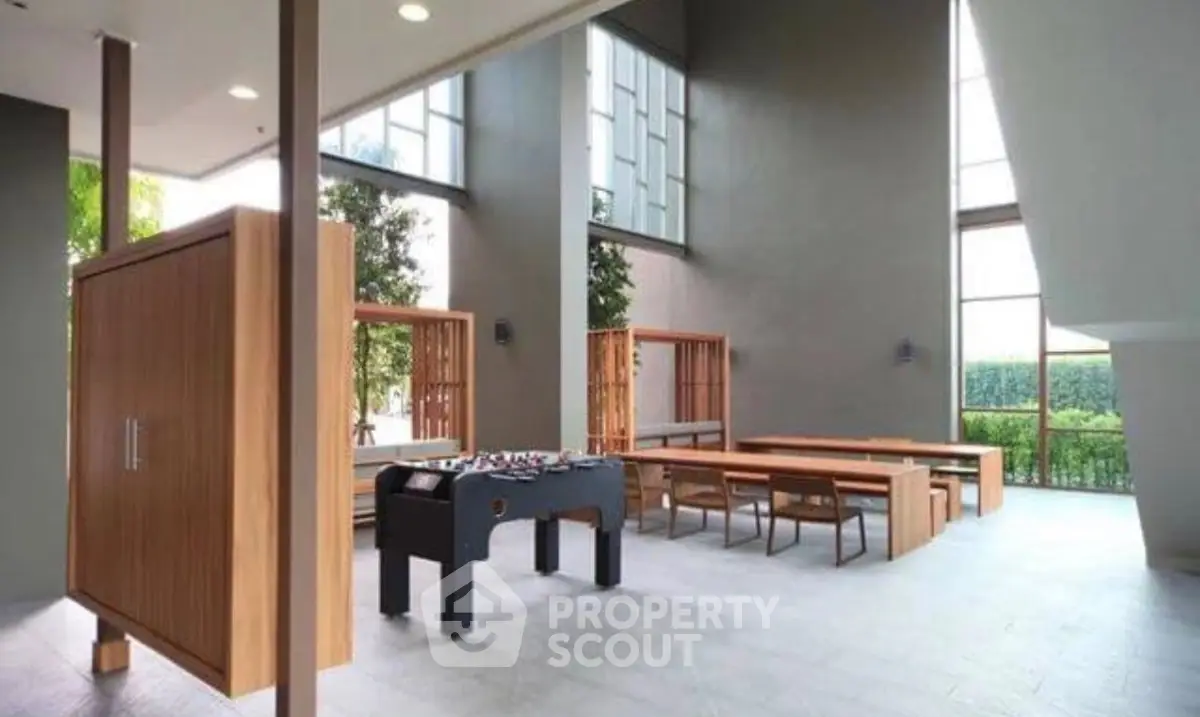 Modern communal area with foosball table and dining setup in a stylish building.