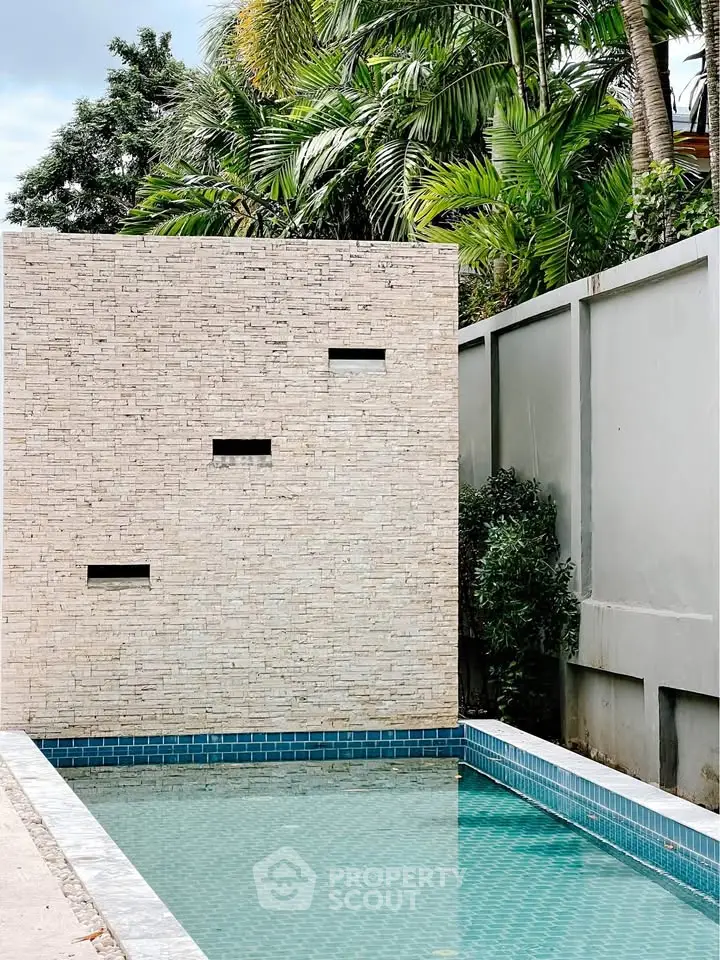Modern outdoor pool with stylish brick wall and lush greenery