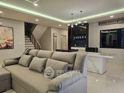 Modern living room with stylish decor and open layout, featuring a plush sofa and elegant lighting.