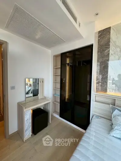 Modern bedroom with sleek design, built-in wardrobe, and stylish vanity in a contemporary apartment.