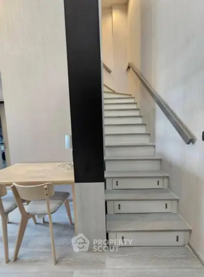 Modern interior with sleek staircase and minimalist dining area, perfect for contemporary living.