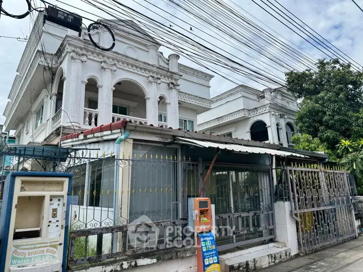 Elegant white villa with classic architecture and gated entrance in urban setting.