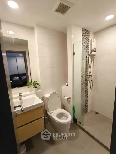 Modern bathroom with sleek fixtures and glass shower enclosure in a contemporary apartment.
