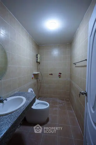 Compact bathroom with tiled walls, modern sink, and toilet in cozy real estate property.