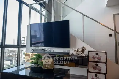 Modern living room with large TV and stylish decor in high-rise apartment