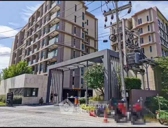 Modern condominium entrance with sleek design and lush greenery, showcasing urban living at its finest.