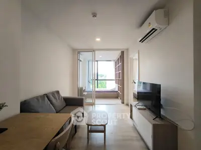 Modern living room with cozy sofa and TV, leading to a bright bedroom with large windows.