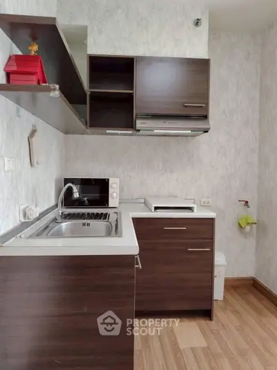 Modern compact kitchen with dark wood cabinets and sleek appliances