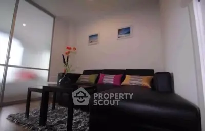 Cozy living room with modern black sofa and vibrant cushions, perfect for relaxation.