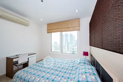 Modern bedroom with city view, featuring stylish decor and ample natural light.