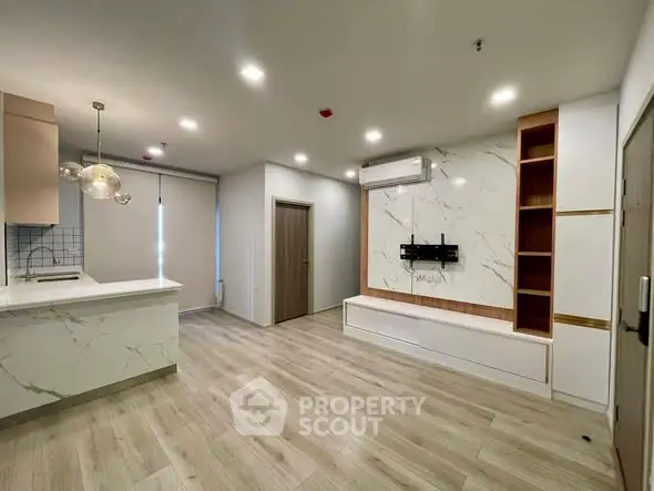 Modern living room with open kitchen, stylish lighting, and elegant wood flooring.