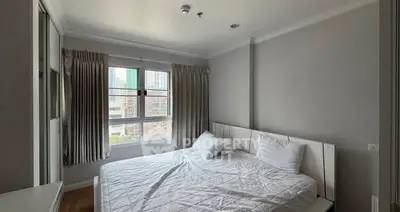 Cozy bedroom with large window and city view, featuring a comfortable bed and neutral decor.