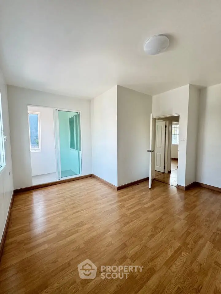 Spacious empty room with wooden flooring and natural light, ideal for customization.