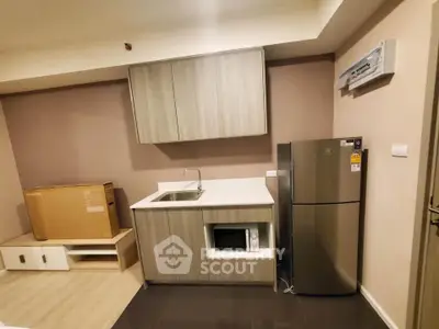 Modern kitchen with sleek cabinetry, stainless steel fridge, and microwave in a compact layout.