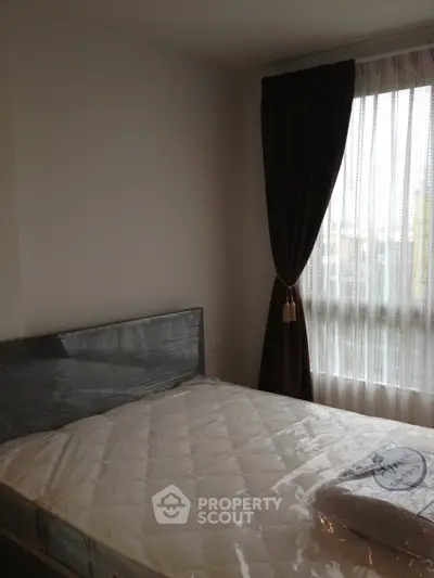 Cozy bedroom with natural light and elegant curtains, perfect for relaxation.