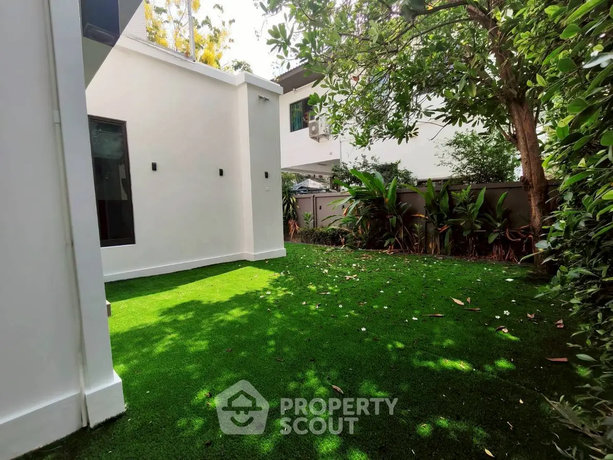 Modern home with lush green garden and sleek white exterior walls, perfect for outdoor relaxation.