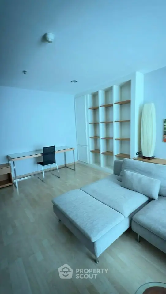 Spacious living room with modern furniture and built-in shelves, perfect for relaxation and productivity.